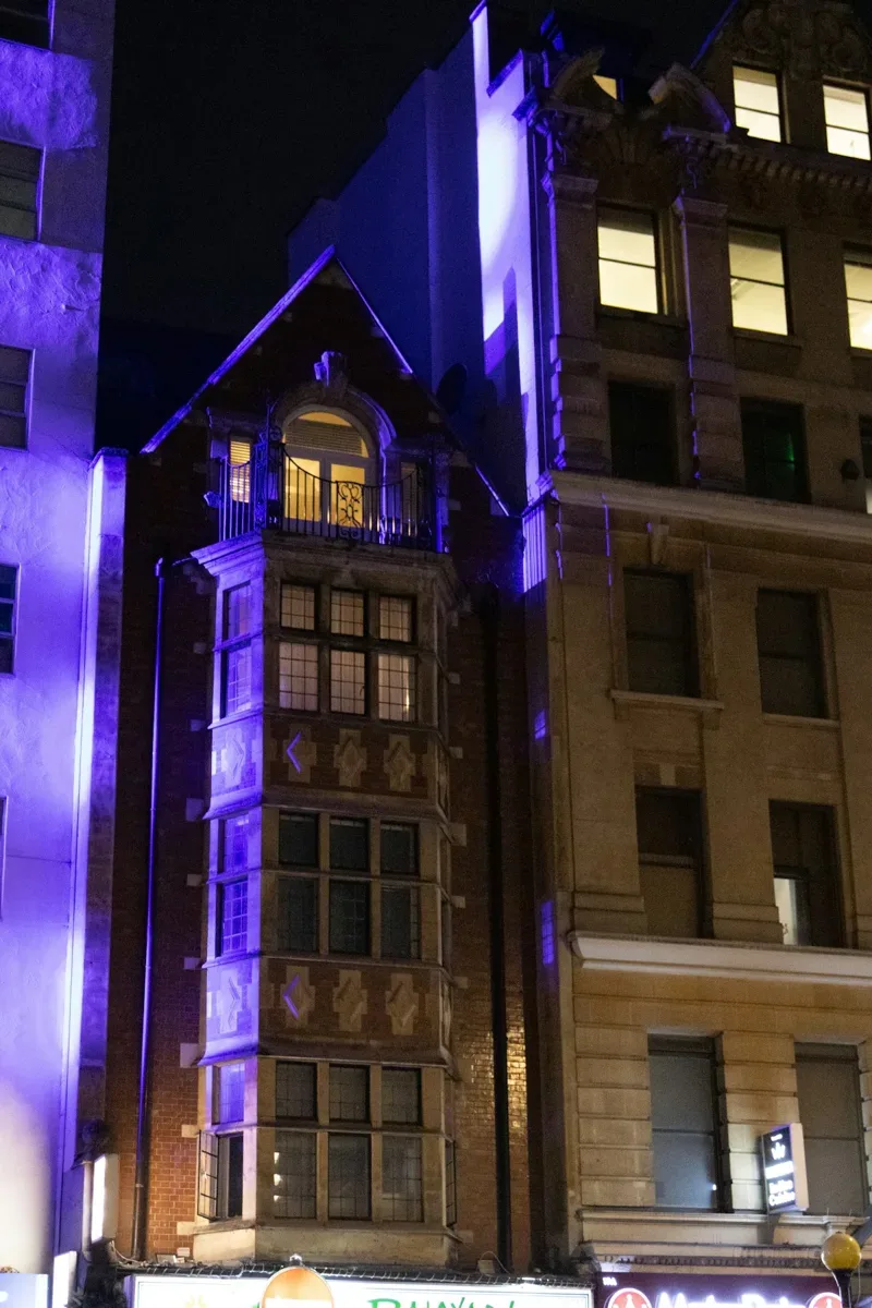 Ornate building elevation illuminated with coloured light at night