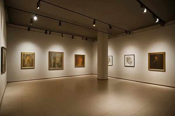 Gallery interior with ceiling spotlights directed towards framed artwork